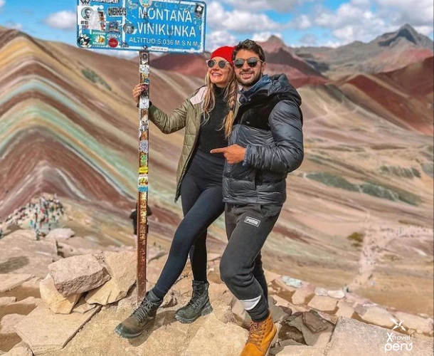 The thrill of reaching the top of the Rainbow Mountain. Capture your achievement at $17,060 \text{ ft}$ with the vibrant backdrop of the Andes. A moment of pride and an unforgettable visual reward.
