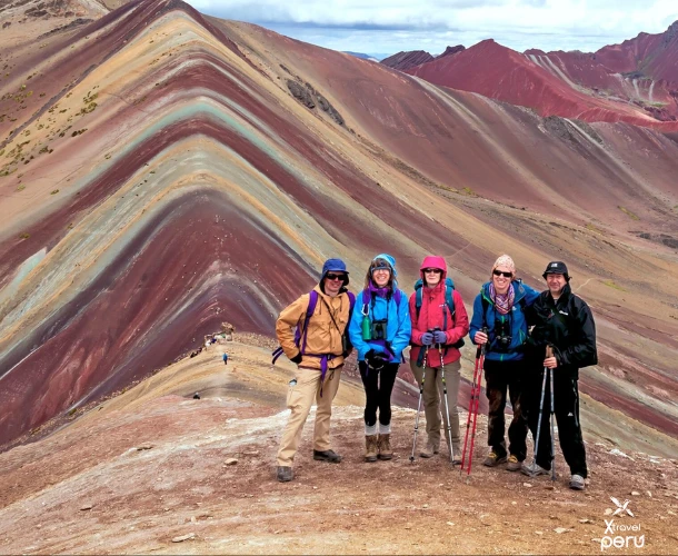 The moment of reward. Capture your achievement at the summit of the Rainbow Mountain ($17,060 \text{ ft}$). Colors intensify under the mid-morning sun. Adventure and success!